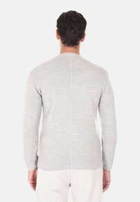 Maglione grigio a maglia con maniche lunghe, scollo rotondo e un motivo testurizzato. Presenta una cucitura centrale e orli a costine ai polsini.