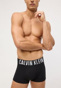 Czarne bawełniane bokserki typu briefs z szerokim elastycznym pasem, na którym widnieje logo "CALVIN KLEIN" w białym kolorze, gładka tekstura, dopasowany krój.
