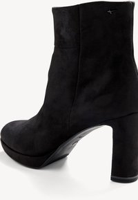 Bottine en daim noir avec bout pointu, talon haut et texture lisse. Présente une couture surpiquée et un design minimaliste sans ornements.