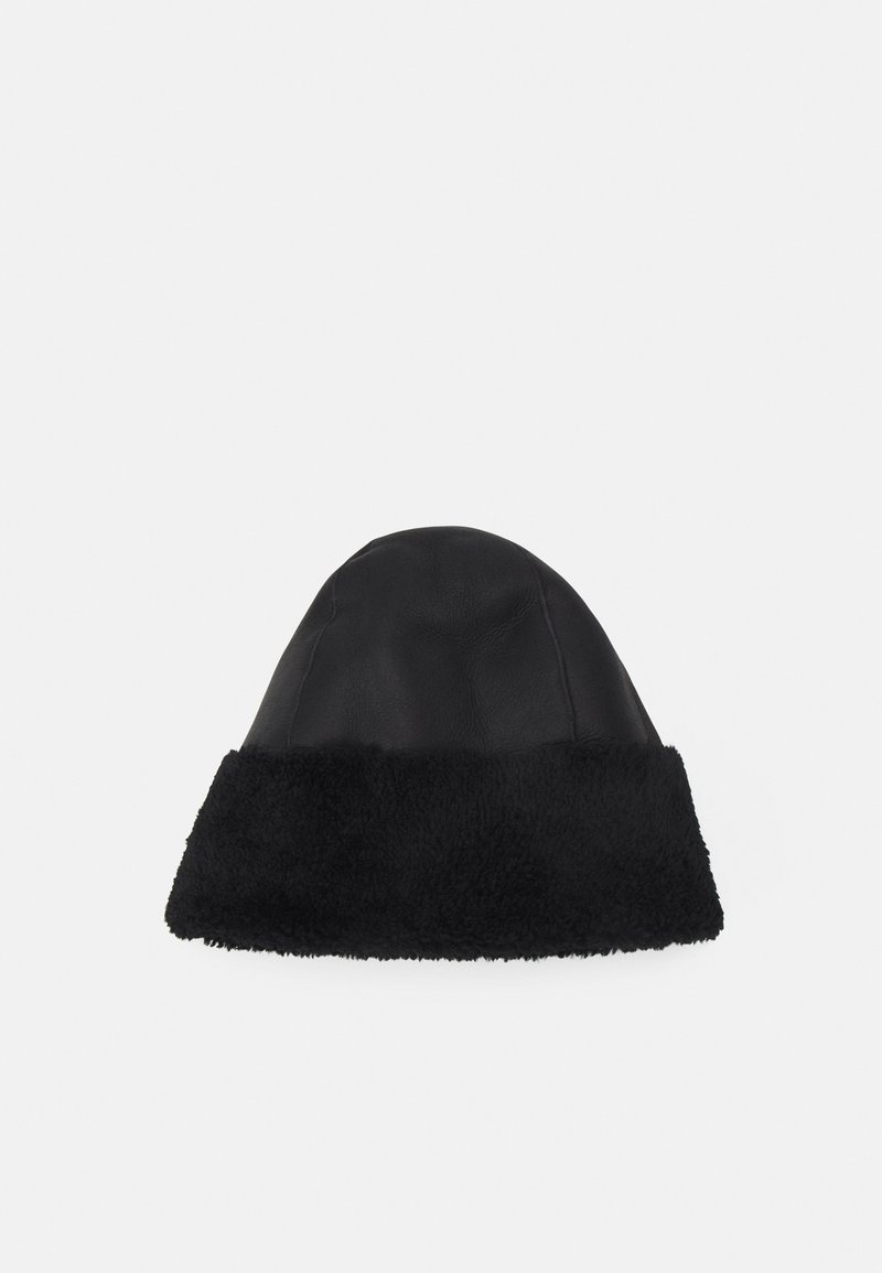 Chapeau noir avec un extérieur en cuir lisse et une bande en fausse fourrure moelleuse à la base. Haut arrondi, conçu pour la chaleur et le confort.