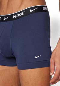 Tamno plavi pamučni bokserice s crnim pojasom na kojem je bijeli Nike logo i mali bijeli swoosh na prednjoj strani.