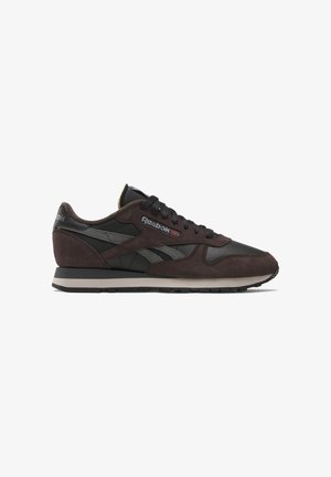 Zapatillas de ante marrón y cuero negro con el logo de Reebok, cordones negros, acentos grises y una suela de goma texturizada. Diseño clásico.