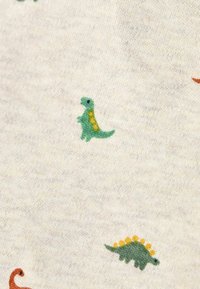 Baumwollstoff mit beigem Hintergrund, der farbenfrohe Dinosaurier-Muster in Grün, Orange und Gelb zeigt. Weiche Textur mit kleinen Motiven.