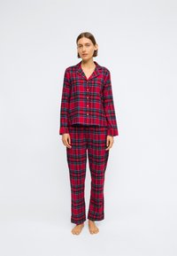 Rød og marineblå rutete pysjamassett med knapp-up langermet topp og løstsittende bukser, laget av myk stoff med en glatt tekstur.