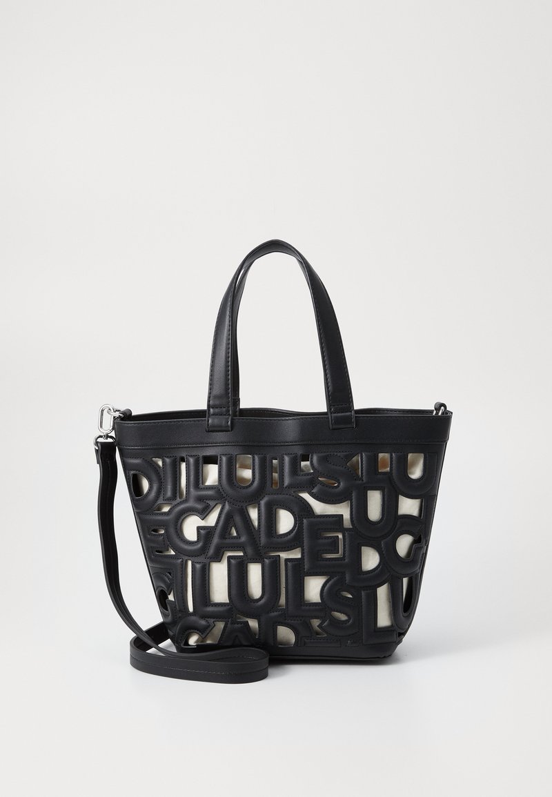 Sac fourre-tout noir avec un design de lettres découpées, doté de deux poignées et d'une bandoulière amovible. Matériau texturé avec des accents lisses.
