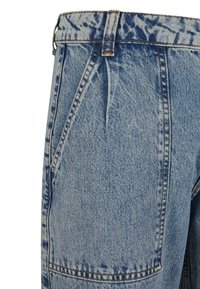 Jean en denim bleu clair avec plis à l'avant, grandes poches latérales inclinées, passants de ceinture et détails de coutures contrastantes.