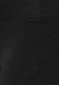 Leggings pretos feitos de um tecido liso e elástico. Apresentam uma cintura sem costura e um corte justo. Design minimalista.