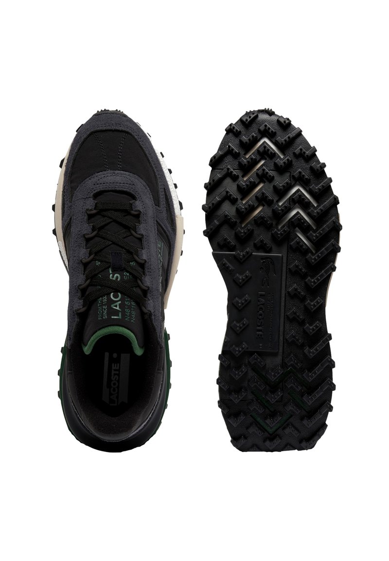 Zapatilla Lacoste negra y gris con suela texturizada que muestra el patrón de la banda de rodadura, vista desde arriba y desde abajo sobre un fondo blanco.