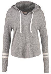 Sudadera gris con mangas largas, cuello con cordón y rayas blancas en las mangas. Textura suave y diseño de corte relajado.
