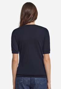 Marinblå kortärmad tröja i mjukt stickat material. Har en rund halsringning och en figursydd nederkant med ribbade detaljer.