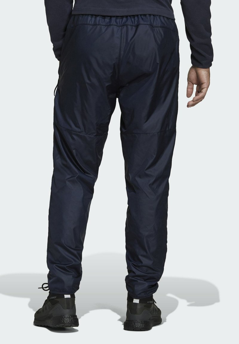 Pantalones deportivos impermeables en color navy con una cinturilla elástica, piernas ajustadas y una textura de tela que parece lisa y duradera. Se ven zapatos deportivos negros.