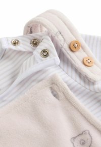 Vauvan bodee, jossa on pehmeä beige fleece ja valkoinen kangas, jossa on vaaleanharmaita raitoja. Sisältää nepparit ja puunappikoristeet.