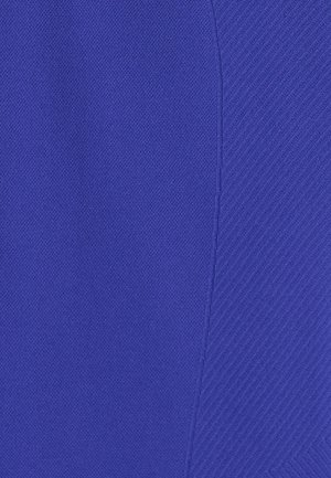 Close-up van helderblauwe stof met twee verschillende texturen: links een glad, strak geweven oppervlak en rechts een diagonaal geribd patroon.