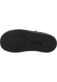 Suela de zapato de goma negra con patrón de agarre texturizado y logotipo central; bordes curvados y material duradero para tracción y comodidad.