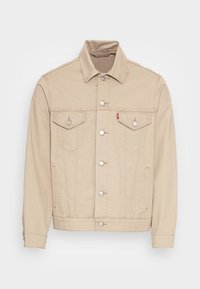 Veste en denim beige au design classique, avec des boutons argentés, deux poches poitrine et des poches latérales. Détails de coutures le long du devant.