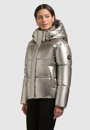 Metallic silver puffer jacket with a high collar, detachable hood, and stitched block pattern. Features side pockets and logo patch on sleeve.