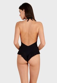 Svart baddräkt med djup V-bak, volangkanter och halterneck-band. Tillverkad av ett slätt, stretcht material.