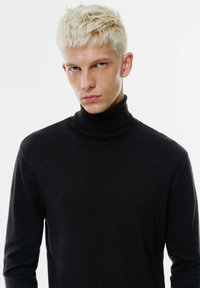 Črna turtleneck pulover z dolgimi rokavi, narejen iz pletenine. Ima tesen ovratnik in minimalističen dizajn, ki se tesno prilega telesu.
