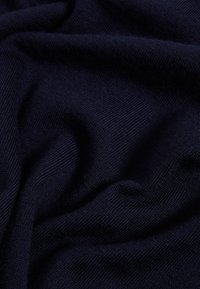 Marineblauer Stoff mit einer feinen, weichen Textur, der eine glatte, leicht reflektierende Oberfläche und subtile, gleichmäßige Strickmuster zeigt.