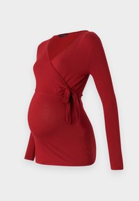 Rotes Still-Wickeloberteil aus weichem Stoff, mit langen Ärmeln, V-Ausschnitt und einem seitlichen Bindegürtel für eine verstellbare Passform, entworfen für Komfort.