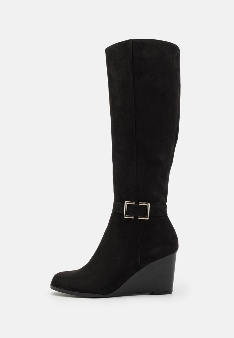 Bottes de cheville noires à talon compensé en daim, avec un design élégant, un détail de boucle sur le côté et une finition lisse et texturée.