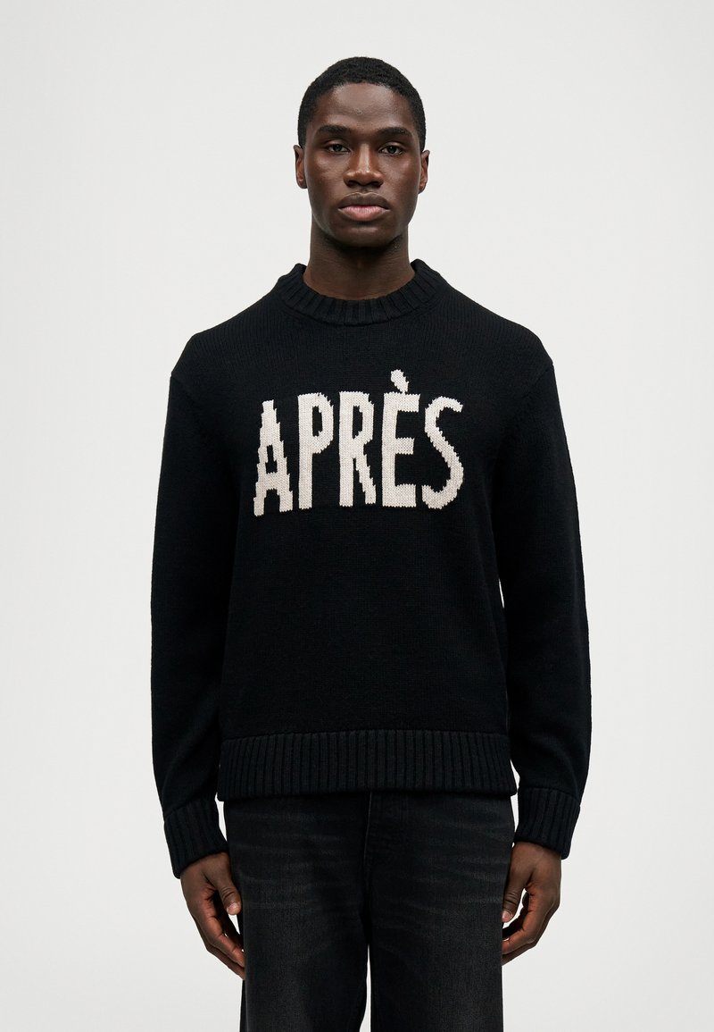 Fekete kötött pulóver, amelyen fehér betűkkel az "APRÈS" szó olvasható, kerek nyakkal és bordázott mandzsettákkal valamint aljjal. Sötét farmernadrággal párosítva.