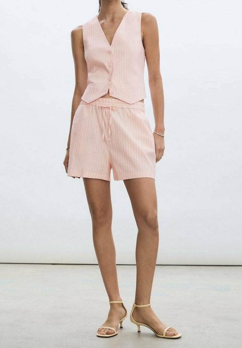 Gilet rose à fines rayures avec boutons, assorti à un short coordonné ; tissu léger, coupe décontractée. Sandales beige à brides complètent la tenue.
