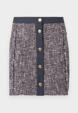 Jupe en tweed tissé bleu marine, rouge et blanc. Elle présente une large ceinture, une fermeture à boutons à l'avant et des poches latérales. Tissu texturé avec des motifs subtils.