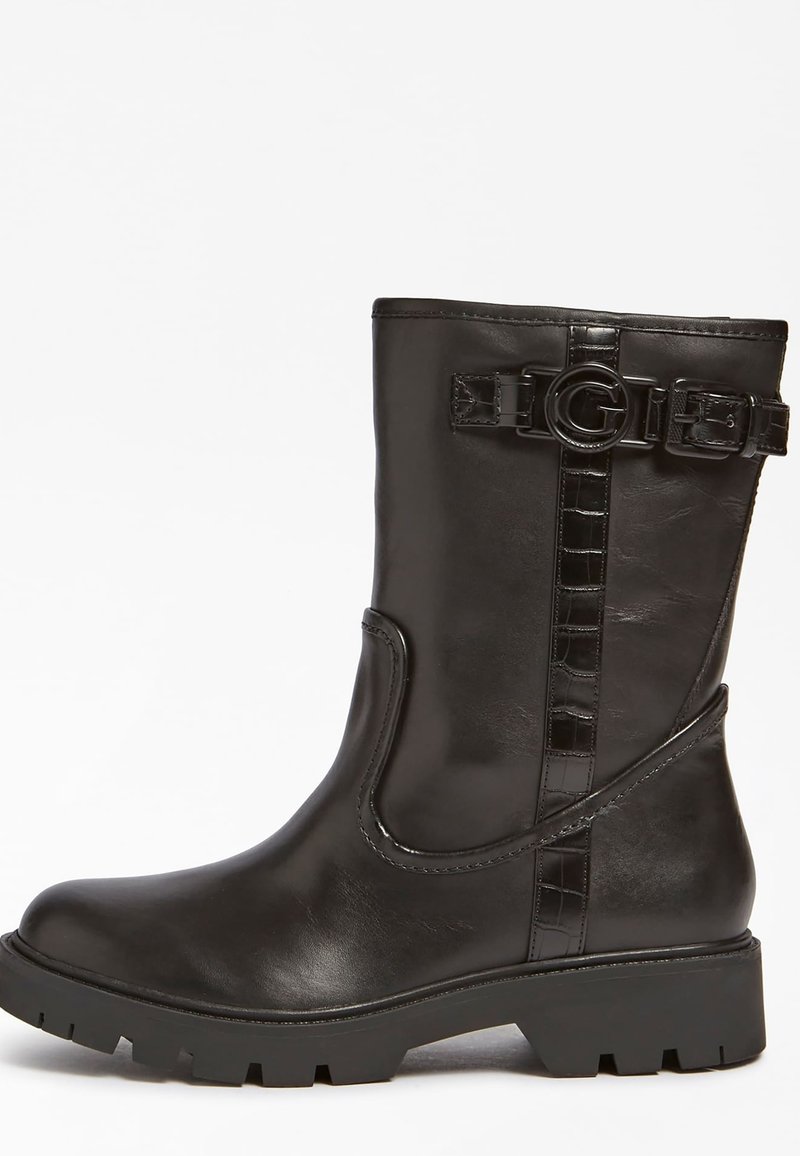 Bottine en cuir noir avec une semelle épaisse, détail de boucle sur le côté et accents de sangle texturés. Fini lisse avec un bout rond.