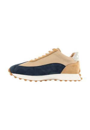 Le sneakers presentano una tomaia in suede beige e blu navy, lacci bianchi e una suola in gomma testurizzata. Gli accenti includono un dettaglio argentato sul tallone.