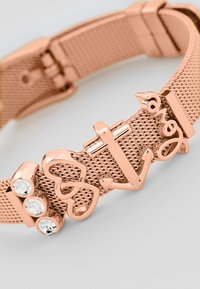 Bracciale in rete rosa con elementi decorativi: scritta "love", ancora e tre gemme trasparenti. Texture liscia e chiusura regolabile.