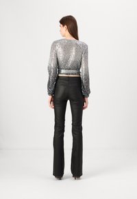 Hõbedane sädeleva alumise servaga crop top pikade puhvis varrukatega ja ühtlase taljega. Ühendatud mustade laiade pükstega. Siledat tekstuuri ja säravat viimistlust.