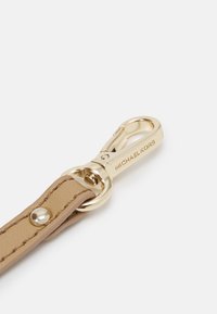 Cinturino in pelle marrone chiaro con chiusura in metallo dorato, dotato di un anello circolare e del testo inciso "MICHAEL KORS" sulla chiusura.