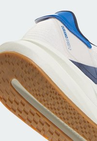 Gros plan sur le talon d'une basket blanche et bleue avec une semelle en caoutchouc brune texturée et le texte "DURAMO SPEED 2" sur le panneau latéral.