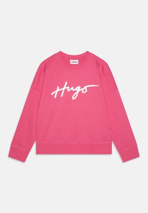 Sweatshirt rosa in materiale morbido con maniche raglan. Presenta il testo cursivo bianco "HUGO" sul davanti e polsini e orlo a coste.