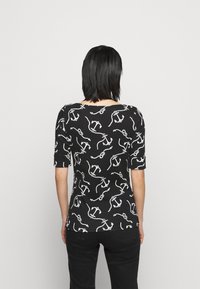 Svart t-shirt med ett vitt ankare och kedjemönster, rund halsringning, korta ärmar och en figursydd silhuett.