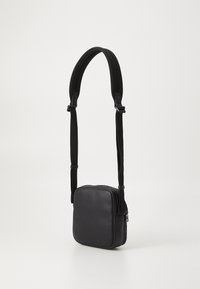 Borsa a tracolla rettangolare nera realizzata in materiale sintetico liscio, con chiusura a zip e tracolla regolabile, progettata per un uso pratico.