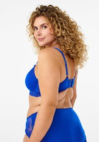 Blue lace bra with adjustable straps, featuring a floral pattern along the edges and a hook-and-eye closure at the back.