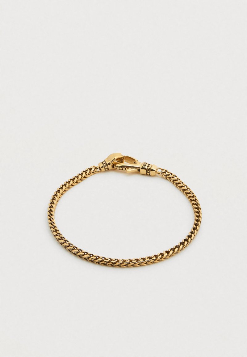 Βραχιόλι με χρυσή αλυσίδα σε στριφτό σχέδιο, με κούμπωμα τύπου αστακός και μικρές διακοσμητικές λεπτομέρειες κοντά στο κούμπωμα. Λείο μεταλλικό υφής.