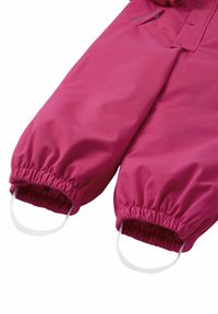 Salopette rosa da esterno con polsini elasticizzati, realizzata in tessuto morbido, con texture liscia e con anelli integrati per una vestibilità sicura.