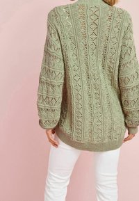 Hellgrüner Strickpullover mit filigranen Spitzenmustern und gerippten Bündchen, der eine lockere Passform und einen hohen Ausschnitt aufweist.