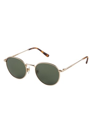 Lunettes de soleil en métal doré avec des verres ronds verts et des accents écaille de tortue sur les embouts des branches. Design fin et léger.