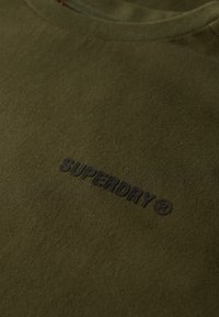 Oliven grøn bomulds t-shirt med rund hals; har et præget sort "SUPERDRY" logo på fronten. Glat tekstur, standard pasform.