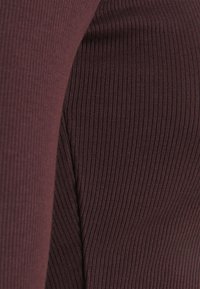 Burgundowa tkana tkanina w prążki z pionowymi liniami, prezentująca miękką teksturę i elastyczny materiał, uwydatniająca szczegółowe wzory w tkaninie.