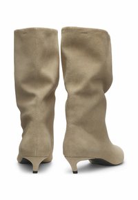 Beige suède kniehoge laarzen met een zachte textuur, slouchy ontwerp en een lage kittenhak. Gladde afwerking zonder zichtbare hardware of accenten.