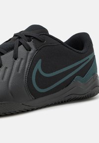 Zwarte sportschoen met een gestructureerde synthetische bovenkant, verweven mesh, groen Nike-logo en een duurzame rubberen zool met profiel.