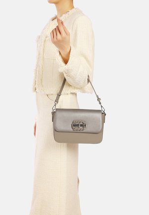 Borsa a tracolla in pelle grigia con una pattina e accessori decorativi. Presenta un motivo a catena sul fermo. Nastro regolabile per indossarla a tracolla.