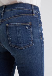 Jeans ajustados de mezclilla azul oscuro que cuentan con cinco bolsillos, costuras en contraste y un pequeño logo bordado en el bolsillo trasero derecho.