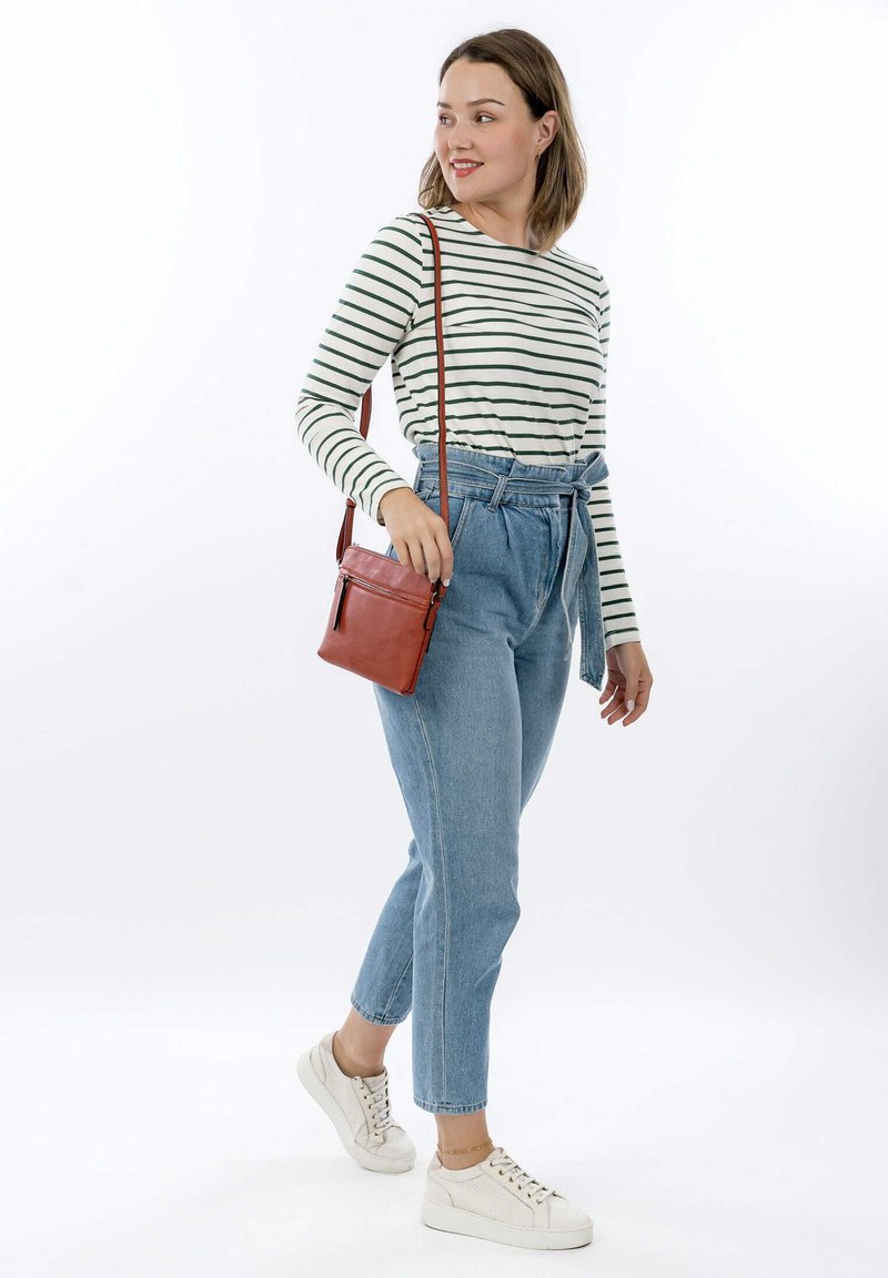Maglietta a maniche lunghe a righe, jeans in denim leggeri a vita alta, borsa a tracolla marrone e sneakers bianche. Outfit casual con vestibilità rilassata.