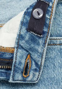Denim tkanina v svetlo modri barvi z oranžnim šivanjem, vključuje zadrgo, gumb z zapiranjem in podrobnost tkanega zanke. Teksturiran in trpežen dizajn.